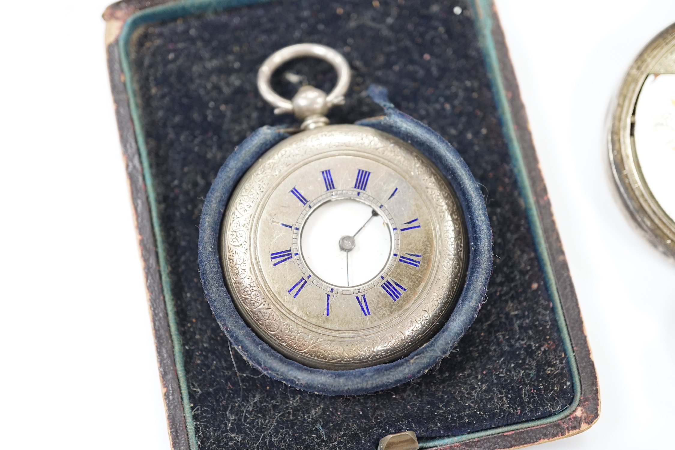Three silver pocket watches and a travel timepiece.